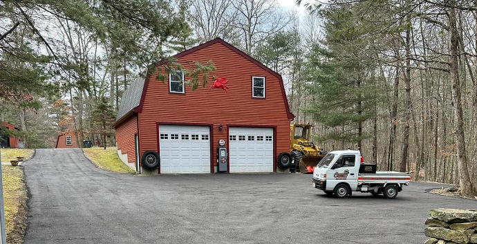 A truck parked in front of a red barn